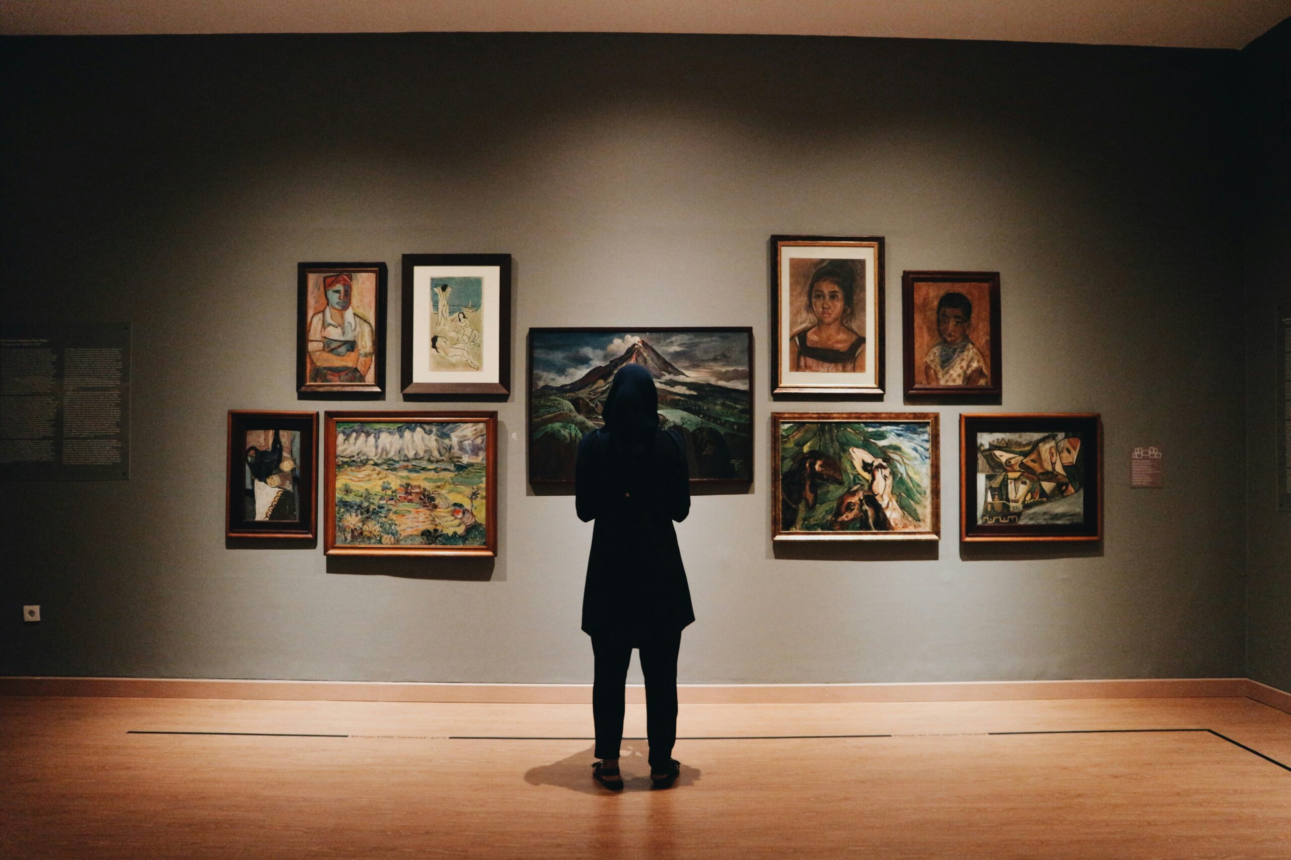 woman in black coat standing in front of paintings, luxury enthusiasts